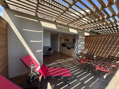 a balcony with pink chairs and a table and a kitchen at Les oliviers 11 Appartement, bord de mer, porto-vecchio in Porto-Vecchio