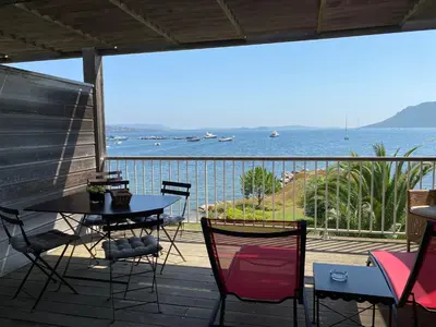 a patio with a table and chairs and a view of the ocean at Les oliviers 11 Appartement, bord de mer, porto-vecchio in Porto-Vecchio
