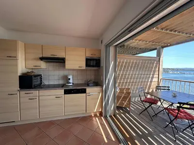 a kitchen with a table and chairs and a balcony at Les oliviers 11 Appartement, bord de mer, porto-vecchio in Porto-Vecchio