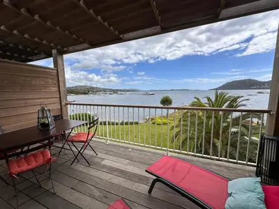 a deck with a table and chairs and a view of the water at Les oliviers 11 Appartement, bord de mer, porto-vecchio in Porto-Vecchio