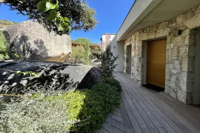 a house with a wooden door next to a building at Villa Cazélie, piscine vue splendide sur le Golfe in Porto-Vecchio