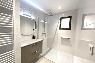 a white bathroom with a shower and a sink at Villa Cazélie, piscine vue splendide sur le Golfe in Porto-Vecchio