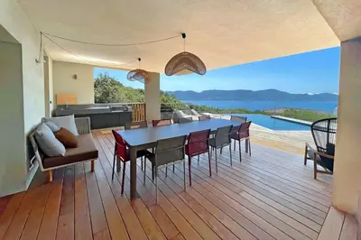 a dining room and living room with a view of the ocean at Villa Cazélie, piscine vue splendide sur le Golfe in Porto-Vecchio