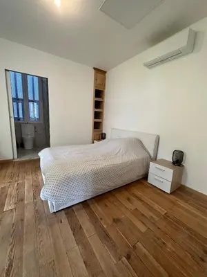a white bedroom with a bed and a wooden floor at Superbe appartement en centre ville in Corte