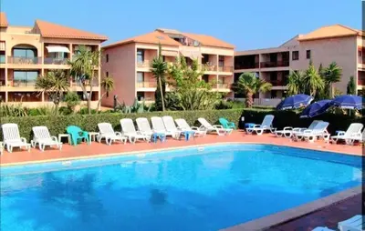 a swimming pool with chairs and umbrellas next to a building at Studio accueillant à San-Nicolao avec vue mer, 27 m² in San-Nicolao