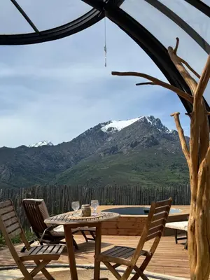 a table and chairs on a deck with a mountain at Dôme étoilé in Vallica