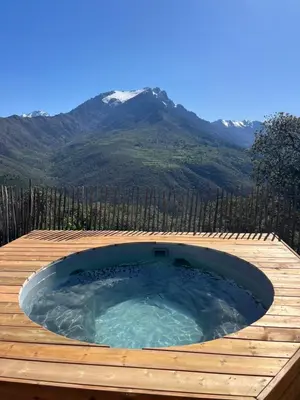 a hot tub on a deck with a mountain in the background at Dôme étoilé in Vallica