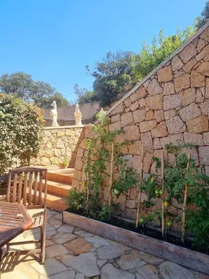 a stone retaining wall with a wooden bench and a table at Villa Propriano vue mer in Viggianello