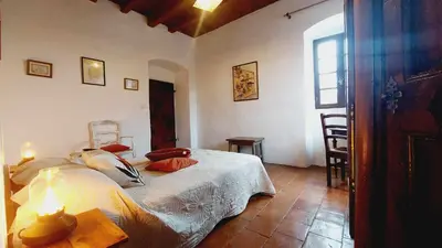 a bedroom with a bed and a table and a window at 1st floor apartment in 18th century character house in Calvi
