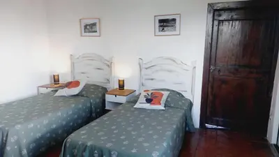 a bedroom with two beds and a wooden floor at 1st floor apartment in 18th century character house in Calvi