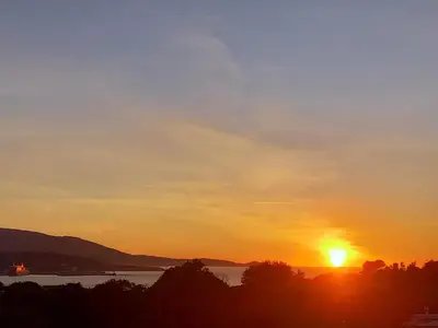 a sunset over a lake with the sun setting at CasaCampanile in Olmeto