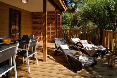 a wooden deck with chairs and a table on it at Résidence & Hotel U Livanti ECOLABEL in Propriano