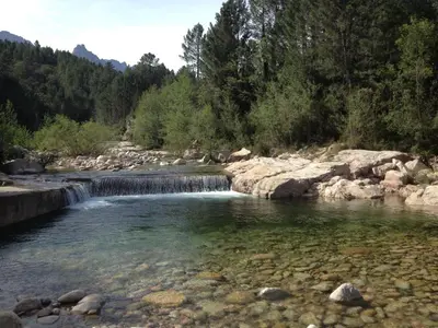 a waterfall in a river with rocks and trees at Plain pied idéalement situé in Sainte-Lucie de Porto-Vecchio