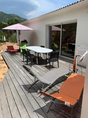 a deck with a table and chairs and an umbrella at Plain pied idéalement situé in Sainte-Lucie de Porto-Vecchio