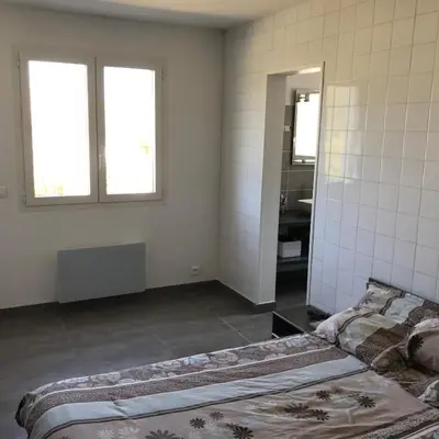 a room with a bed and a bathroom with a mirror at Plain pied idéalement situé in Sainte-Lucie de Porto-Vecchio