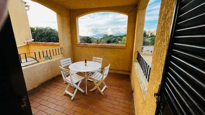 a balcony with a table and chairs and a window at T2 sur hauteur de Porticcio avec vue sur la baie d Ajaccio in Porticcio