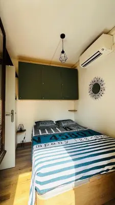 a bedroom with a bed with blue and white striped sheets at T2 sur hauteur de Porticcio avec vue sur la baie d Ajaccio in Porticcio