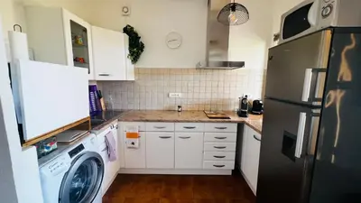 a kitchen with white cabinets and a washer and dryer at T2 sur hauteur de Porticcio avec vue sur la baie d Ajaccio in Porticcio