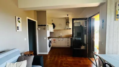 a living room with a kitchen with a refrigerator at T2 sur hauteur de Porticcio avec vue sur la baie d Ajaccio in Porticcio