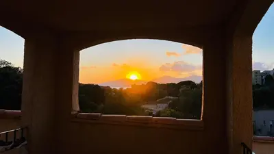 a view of the sunset through a window at T2 sur hauteur de Porticcio avec vue sur la baie d Ajaccio in Porticcio
