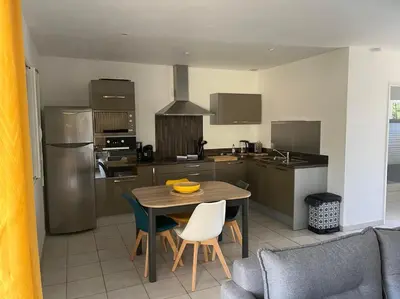 a kitchen with a wooden table and chairs and a table and a kitchen with at Appartement Cosy à Lecci , Porto Vecchio in Lecci