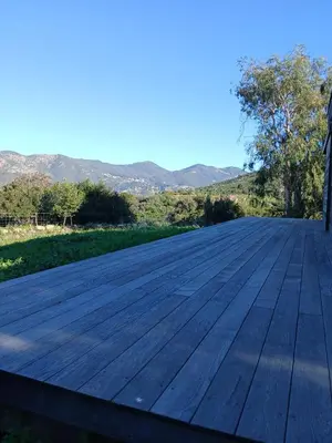 a wooden deck with mountains in the background at Havre de paix à 10 minutes de la mer et 15 minutes d'Ajaccio in Appietto
