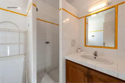 a bathroom with a sink and a mirror and a shower at Les Hauts de Pavellone in Porto-Vecchio