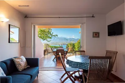 a living room with a couch and a table and chairs at Les Hauts de Pavellone in Porto-Vecchio