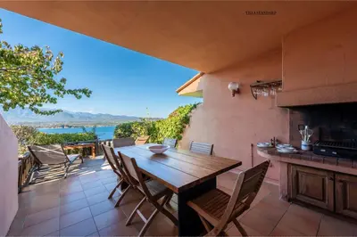 an outdoor patio with a wooden table and chairs at Les Hauts de Pavellone in Porto-Vecchio