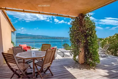 a table and chairs on a deck with a view of the water at Les Hauts de Pavellone in Porto-Vecchio