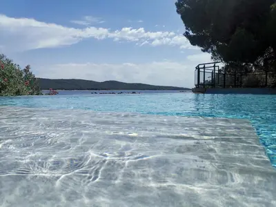 a pool of water with a view of the ocean at La Parenthèse Corse - T2 cabine vue mer in Pianottoli-Caldarello