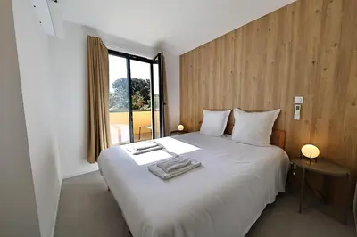 a bedroom with a large white bed with a window at La Parenthèse Corse - T2 cabine vue mer in Pianottoli-Caldarello