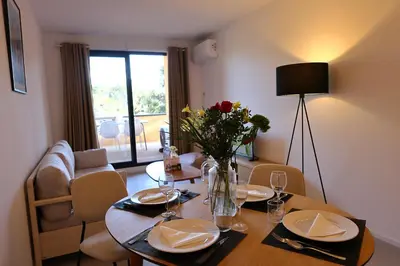 a dining room table with a vase of flowers on it at La Parenthèse Corse - T2 cabine vue mer in Pianottoli-Caldarello