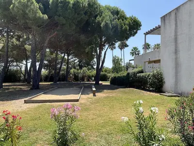 a park with a bench and some trees and flowers at Appartement cosy avec wifi en bord de mer in Poggio-Mezzana