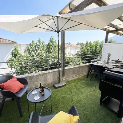a patio with an umbrella and tables and a piano at Appartement cosy avec wifi en bord de mer in Poggio-Mezzana