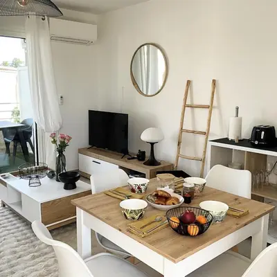 a living room with a table and a television at Appartement cosy avec wifi en bord de mer in Poggio-Mezzana