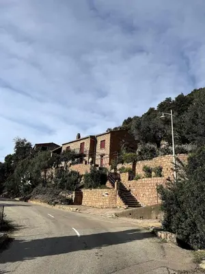 a building on the side of a hill with a road at Résidence Hôtelière CASA DI BABBÒ, Porto in Porto Ota