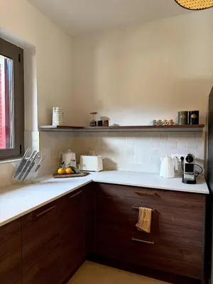 a kitchen with white counter tops and wooden cabinets at Résidence Hôtelière CASA DI BABBÒ, Porto in Porto Ota