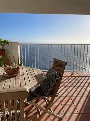 a wooden table and chair on a balcony overlooking the ocean at Penthouse Amazing View in Bonifacio