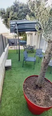 a tree in a red bowl next to a table and benches at Entre mer et montagne in Peri