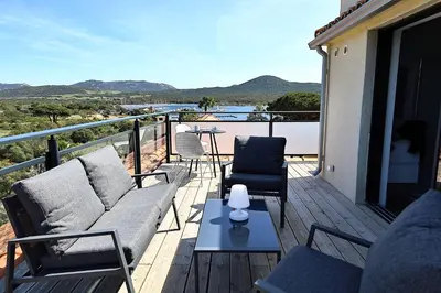 a balcony with a couch and chairs and a table at Superbe studio - Terrasse 360 avec vue mer in Pianottoli-Caldarello
