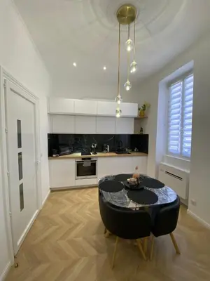 a white kitchen with a black table and a dining room at Grand T2 Cours Napoléon A in Ajaccio