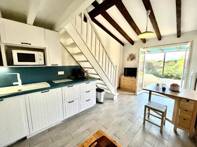 a kitchen with white cabinets and a table and a staircase at Appartement Studio Porticcio Paesolu 313 in Porticcio