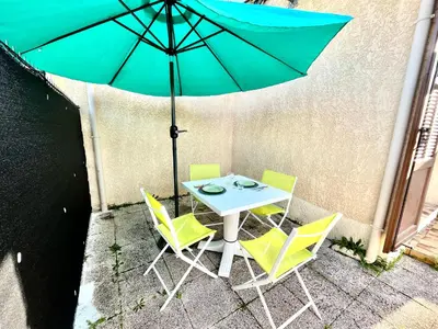 a table and chairs with an umbrella on a patio at Appartement Studio Porticcio Paesolu 313 in Porticcio