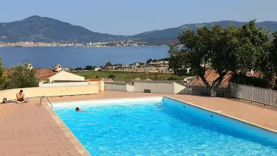 a man sitting in a swimming pool next to a lake at Appartement Studio Porticcio Paesolu 313 in Porticcio