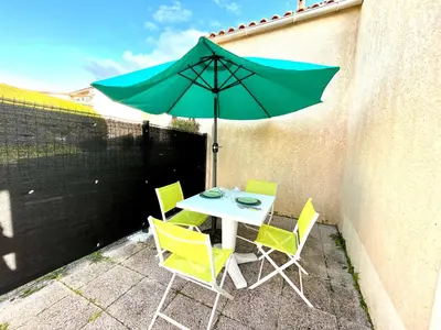 a table and chairs with a green umbrella on a patio at Appartement Studio Porticcio Paesolu 313 in Porticcio