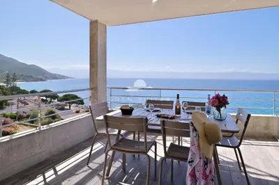 a table on a balcony with a view of the ocean at Résidence Eden Suites in Ajaccio