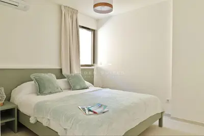 a white bedroom with a bed with a window at Résidence Eden Suites in Ajaccio