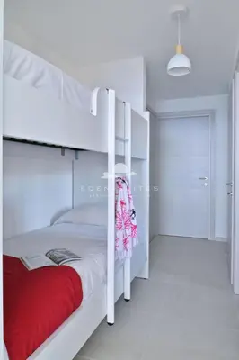 a bedroom with a white bunk bed with a red blanket at Résidence Eden Suites in Ajaccio