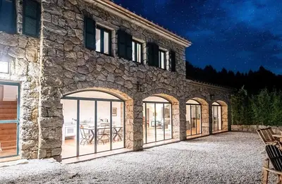 an external view of a stone building with glass doors at La tonnelerie, belle villa pour 9 personnes au coeur d'un vignoble avec piscine in Sartène